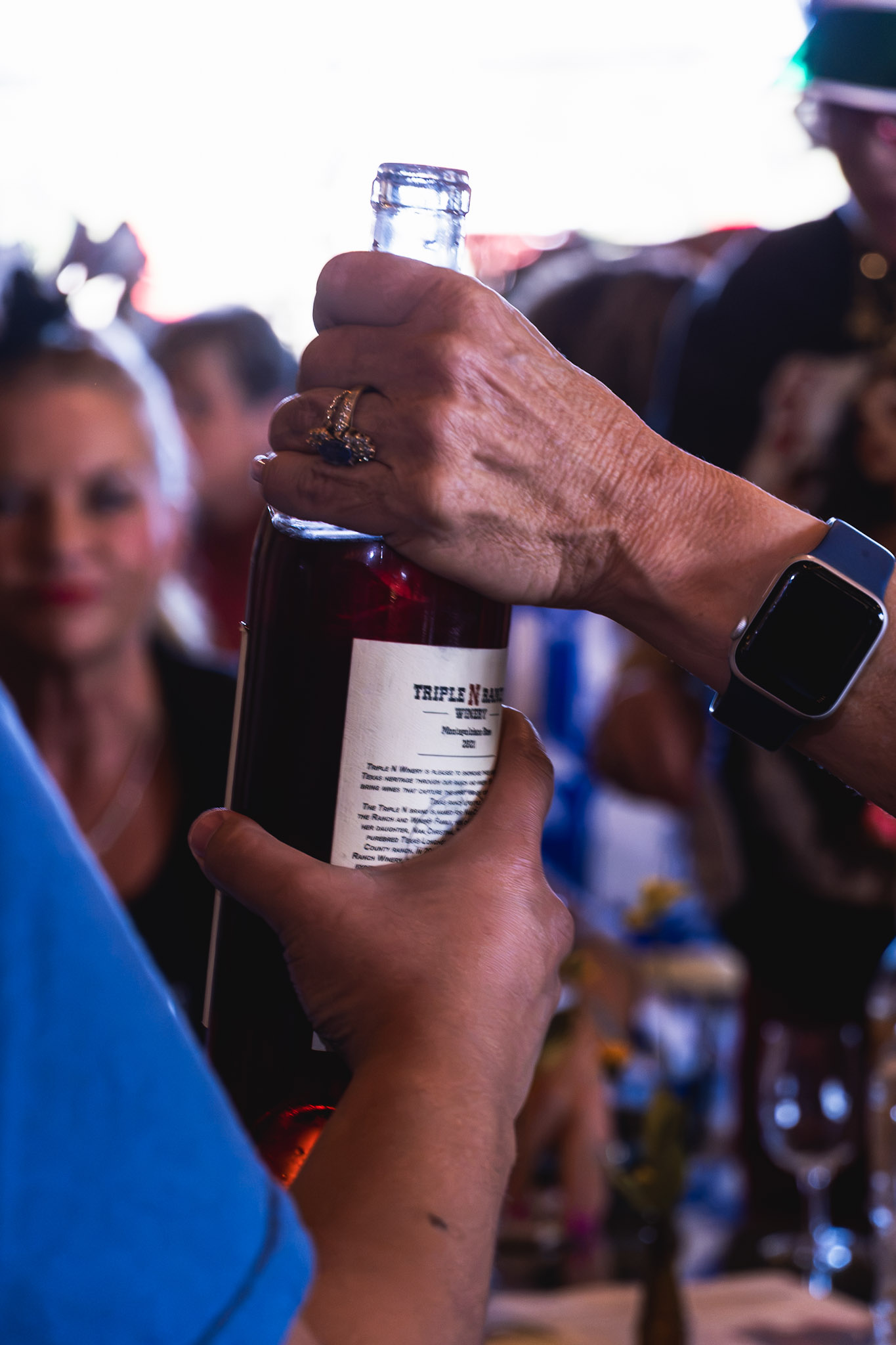 Two hands holding a bottle of wine during an event